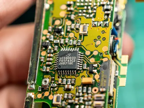 Geöffneter Funkschlüssel: Platine mit Chip und Batteriekontakt zwischen zwei Fingern