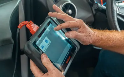 Diagnosegerät mit Kabel zum Fahrzeug in den Händen eines Mechanikers