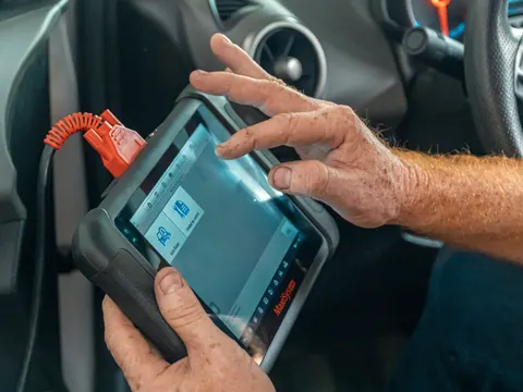 Diagnosegerät mit Kabel zum Fahrzeug in den Händen eines Mechanikers